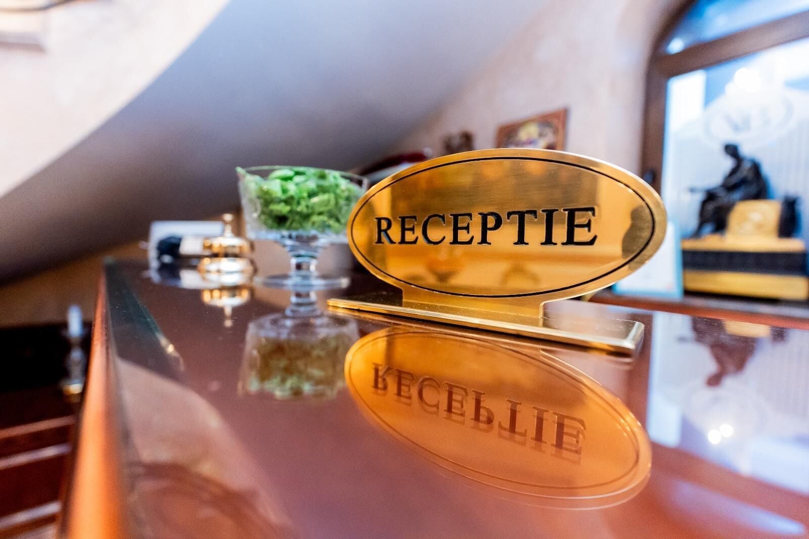 A reception desk with a reflective surface and the word "RECEPTION" engraved on it.