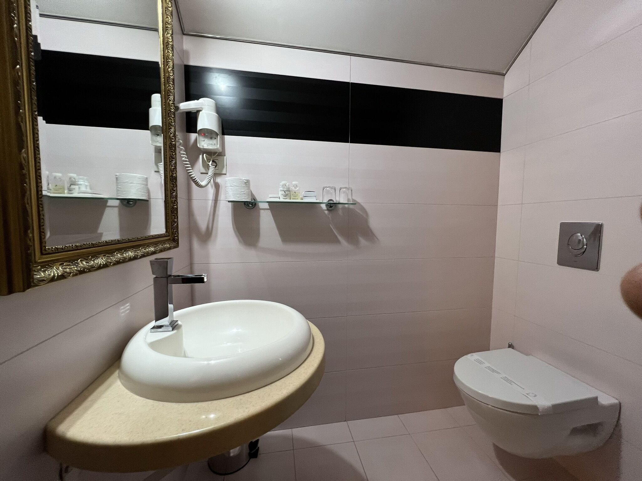 A bathroom with a sink, toilet, and a mirror with a decorative frame.