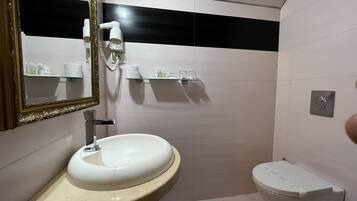 A bathroom with a sink, toilet, and a mirror with a decorative frame.