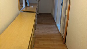 A hallway with a wooden floor, a long table with drawers, a mirror, and a door with a no-smoking sign. - NestOaseWHV Küstenzimmer im Stadtherz (Wilhelmshaven)