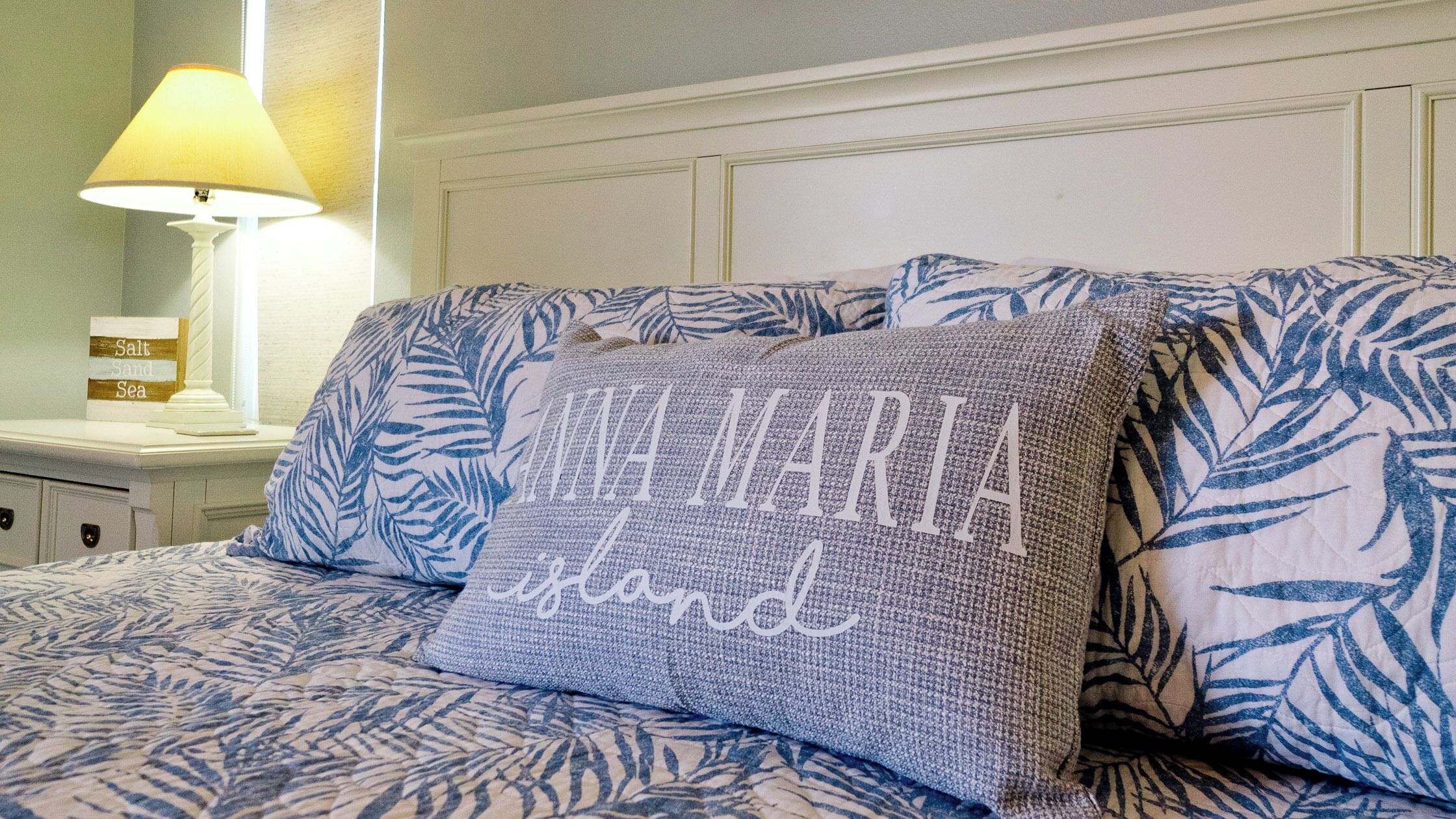 Una cama con almohadas estampadas y una mesita de noche con una lámpara y un adorno.