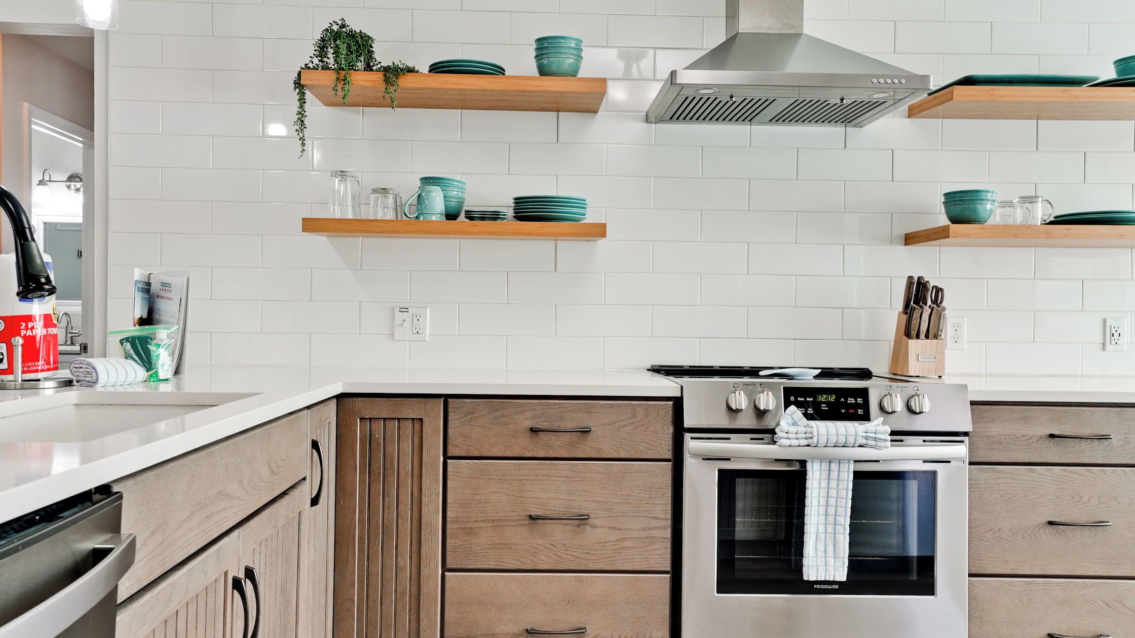 A modern kitchen with white subway tiles, wooden cabinets, and stainless steel appliances.