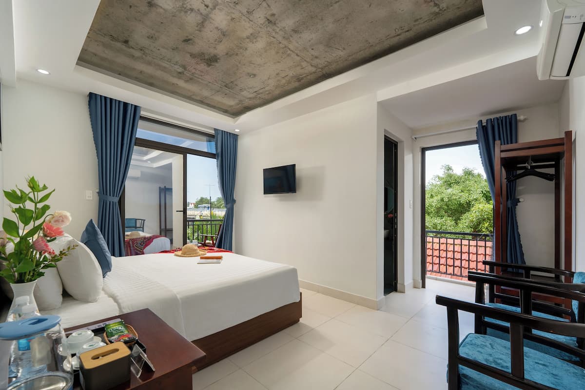 A hotel room with a bed, bedside table, TV, and a balcony with a view.