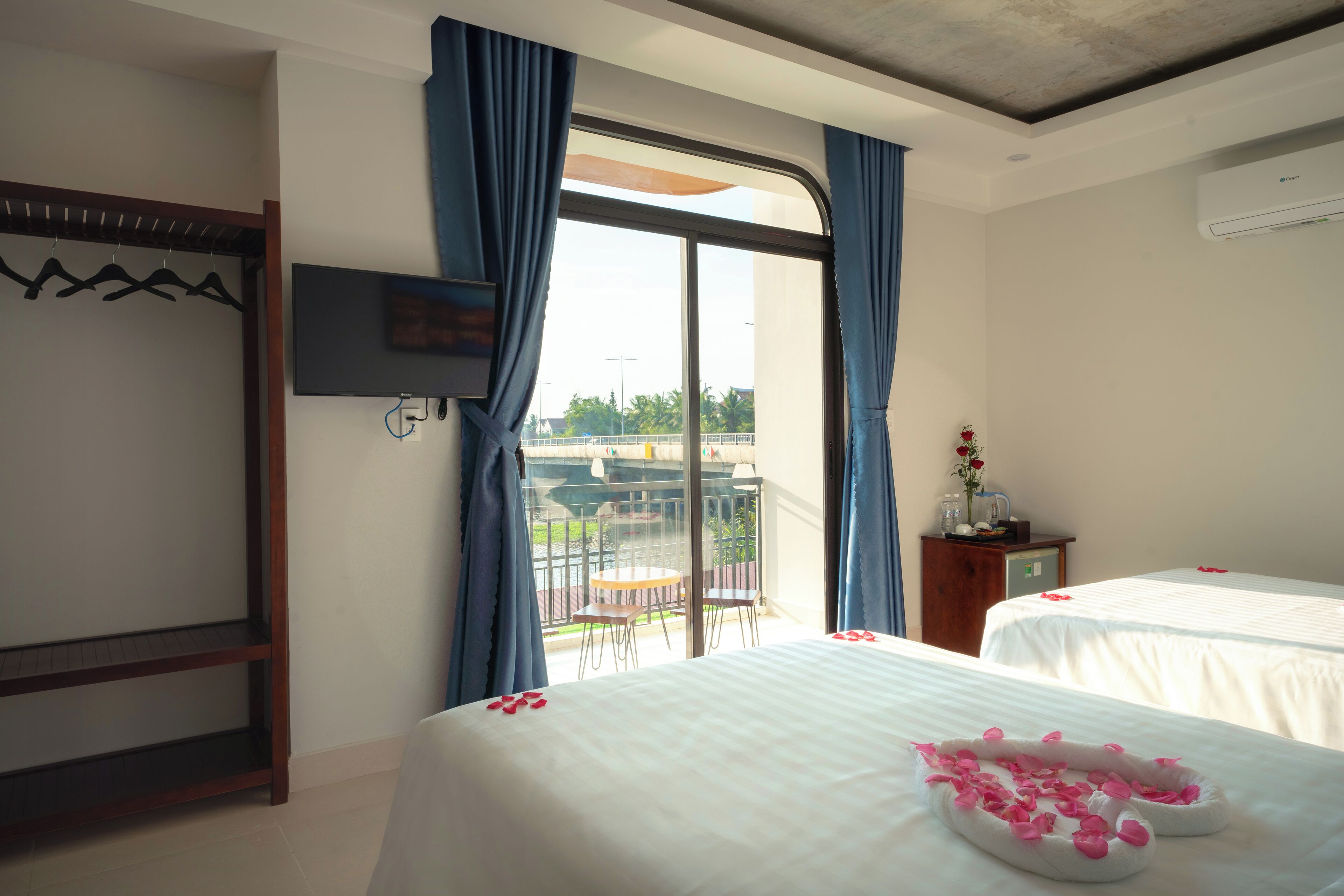 A hotel room with two beds, a balcony, a TV, and a wooden shelf.