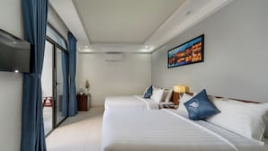 Ein Hotelzimmer mit zwei Betten, einem Flachbildfernseher, einem Gemälde und einer Schiebeglastür.
