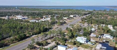 An aerial view of a residential area with houses, a road, and a body of water in the background.