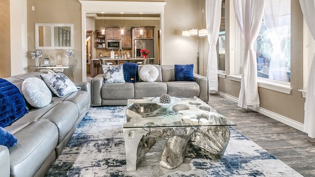 A living room with a sofa, coffee table, and a kitchen in the background.