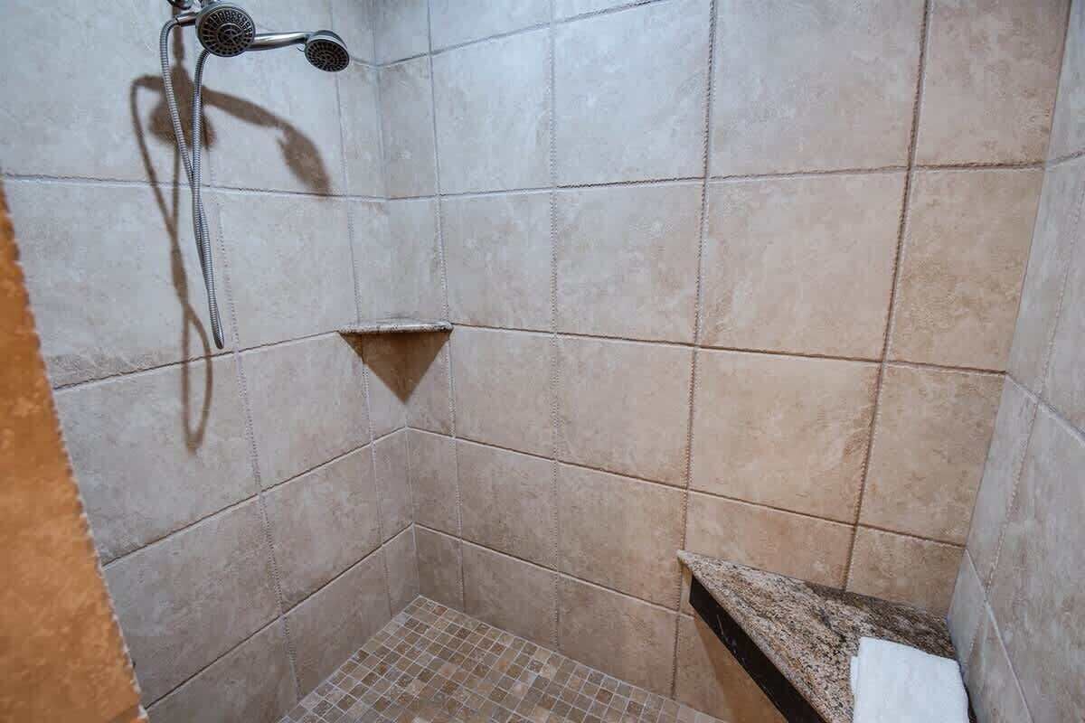 A small, tiled shower area with a showerhead and a towel rack.