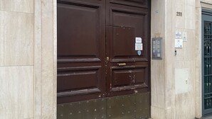 Eine große, dunkelbraune Doppeltür mit Metall-Schutzleiste, eingelassen in eine beige Sandsteinstenwand, oberhalb befindet sich die Zahl '255'.