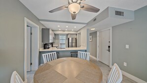 Una cocina moderna con una isla central, armarios blancos y un refrigerador de acero inoxidable.