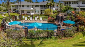A resort with a pool area, lounge chairs, and a waterfall. - Kauai Plantation At Princeville 1121 3 Bedroom Condo (Princeville)