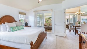 A spacious bedroom with a large bed, a ceiling fan, and a view of an outdoor patio area. - Kauai Plantation At Princeville 1121 3 Bedroom Condo (Princeville)