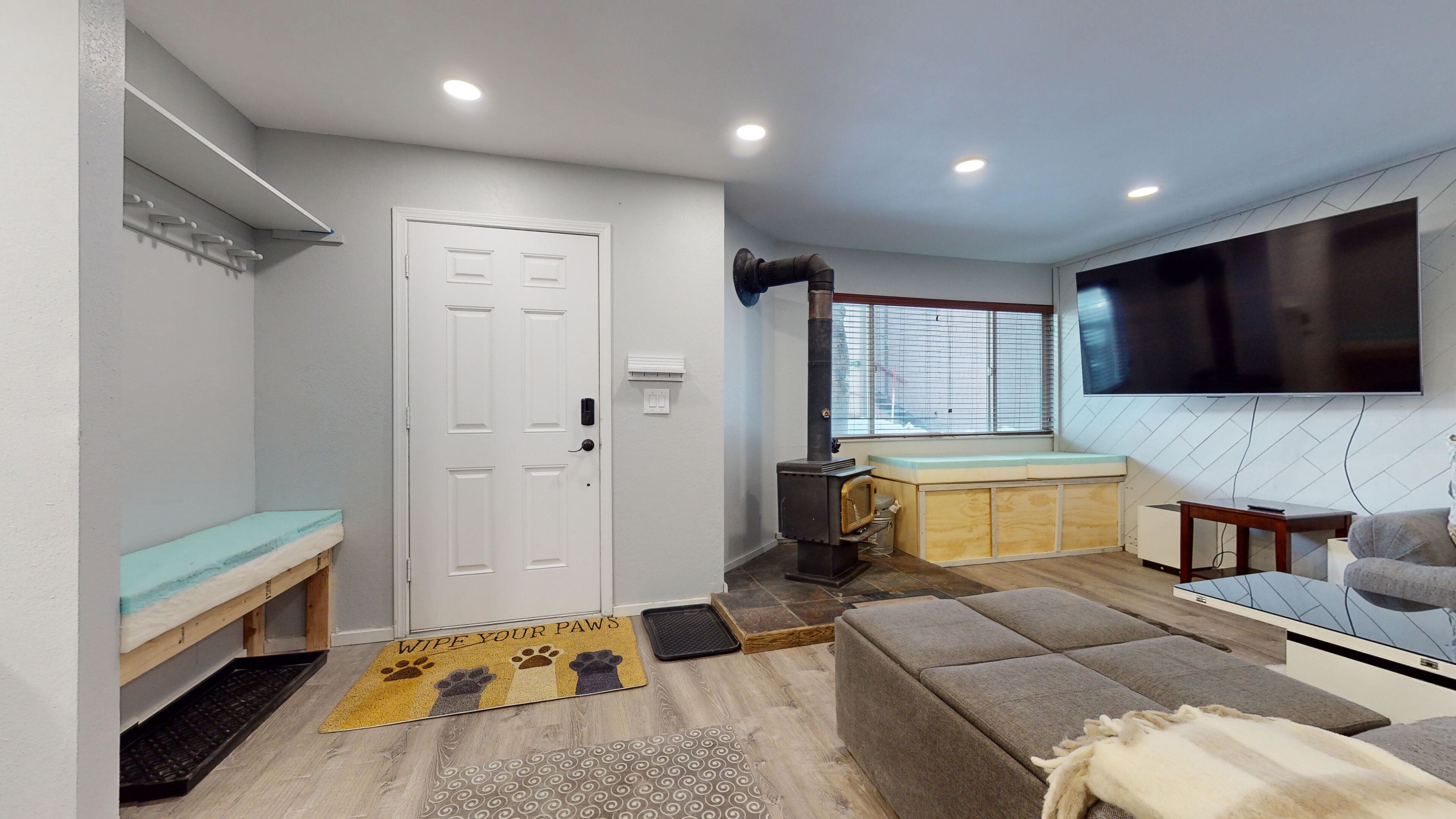 A modern living room with a sofa, a TV, a fireplace, and a window.