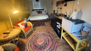 Una habitación de hotel compacta con cama, escritorio, silla, lámpara y televisor.