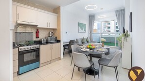 Een moderne keuken met een gasfornuis, magnetron en broodrooster, en een eethoek met een tafel voor twee personen.