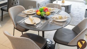 Een eethoek met een ronde tafel voor vier personen, compleet met borden, bestek en een schaal fruit.