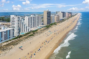 Un paisaje urbano costero con una extensa playa de arena bordeada de altos hoteles y una vista despejada del océano.