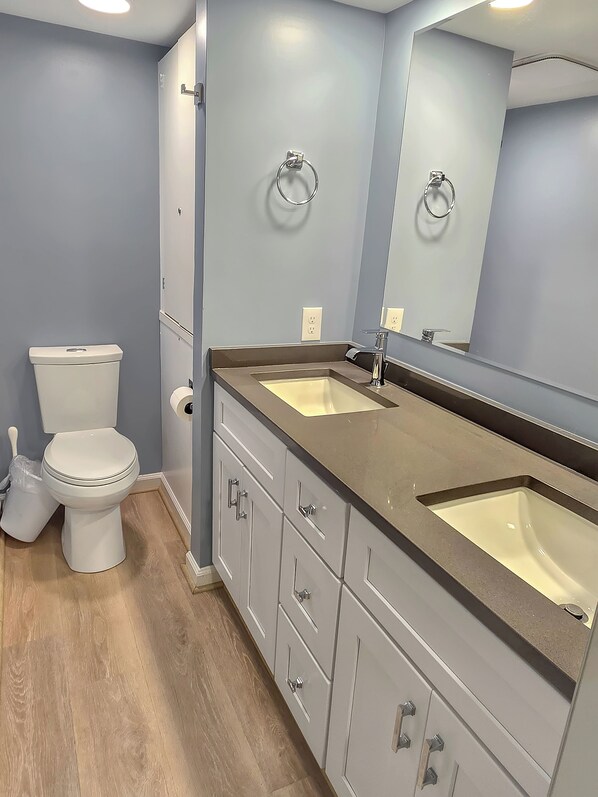 A bathroom with a toilet, two sinks, and a mirror. - Direct Oceanfront Condo with Outdoor Pool - Amazing Beachfront location! Pyramid Building 3C (Ocean City)