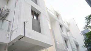 Un edificio a più piani con pareti esterne bianche, finestre visibili e tubature esterne.