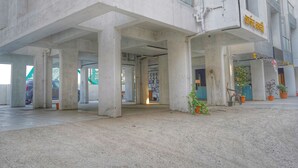 Un edificio con struttura in cemento, ampie colonne e un cartello con del testo.