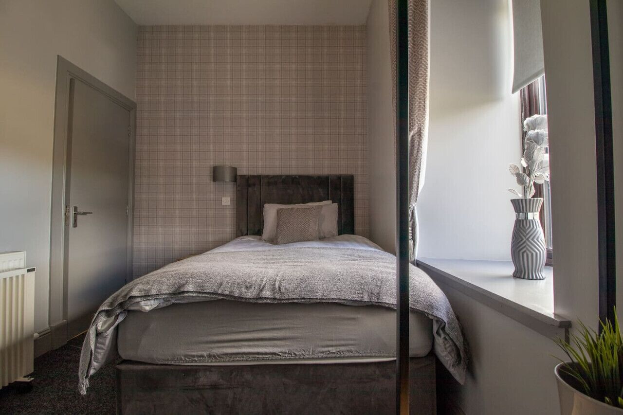 Une chambre à coucher avec un lit, une table de chevet, une fenêtre donnant sur un paysage agréable et un radiateur.