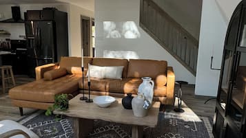 A spacious living area with a sectional sofa, a coffee table, and a large window.