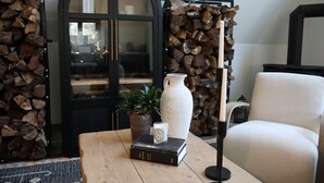 A room with a wooden coffee table, a potted plant, a vase, and a chair. - Pocono Lakefront A-Frame Cabin (Pocono Lake)