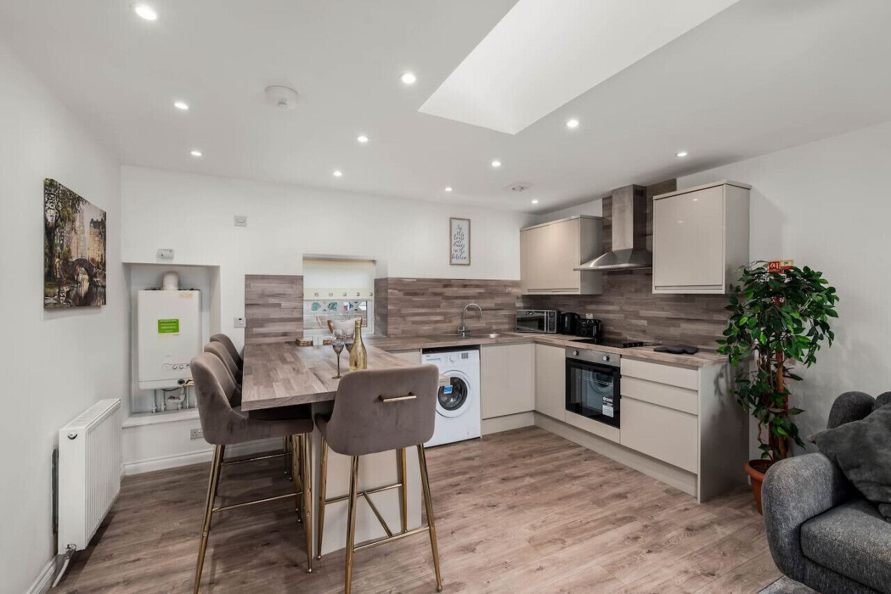 Una cocina moderna con una isla central, electrodomésticos integrados y una zona de comedor con taburetes de bar.