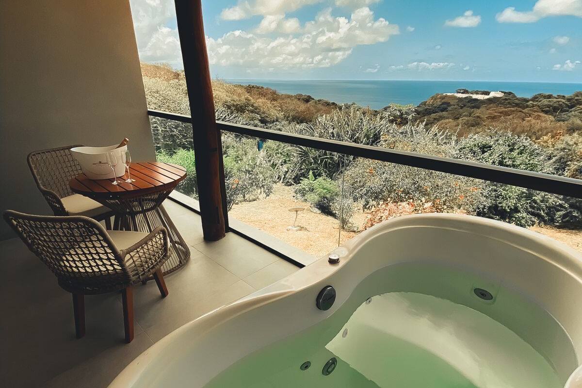 Uma varanda com hidromassagem, uma mesa com balde e copo, e vista para uma paisagem desértica.