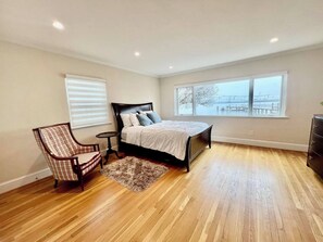 Relax in this serene bedroom with a large bed, comfortable chair, and natural views from the two windows.