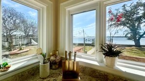 A kitchen with large windows overlooking a backyard and a body of water. - Waterview Oasis by Buckroe Beach (Hampton)