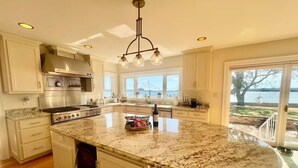 A spacious kitchen with a large island, stainless steel appliances, and a view of the water. - Waterview Oasis by Buckroe Beach (Hampton)
