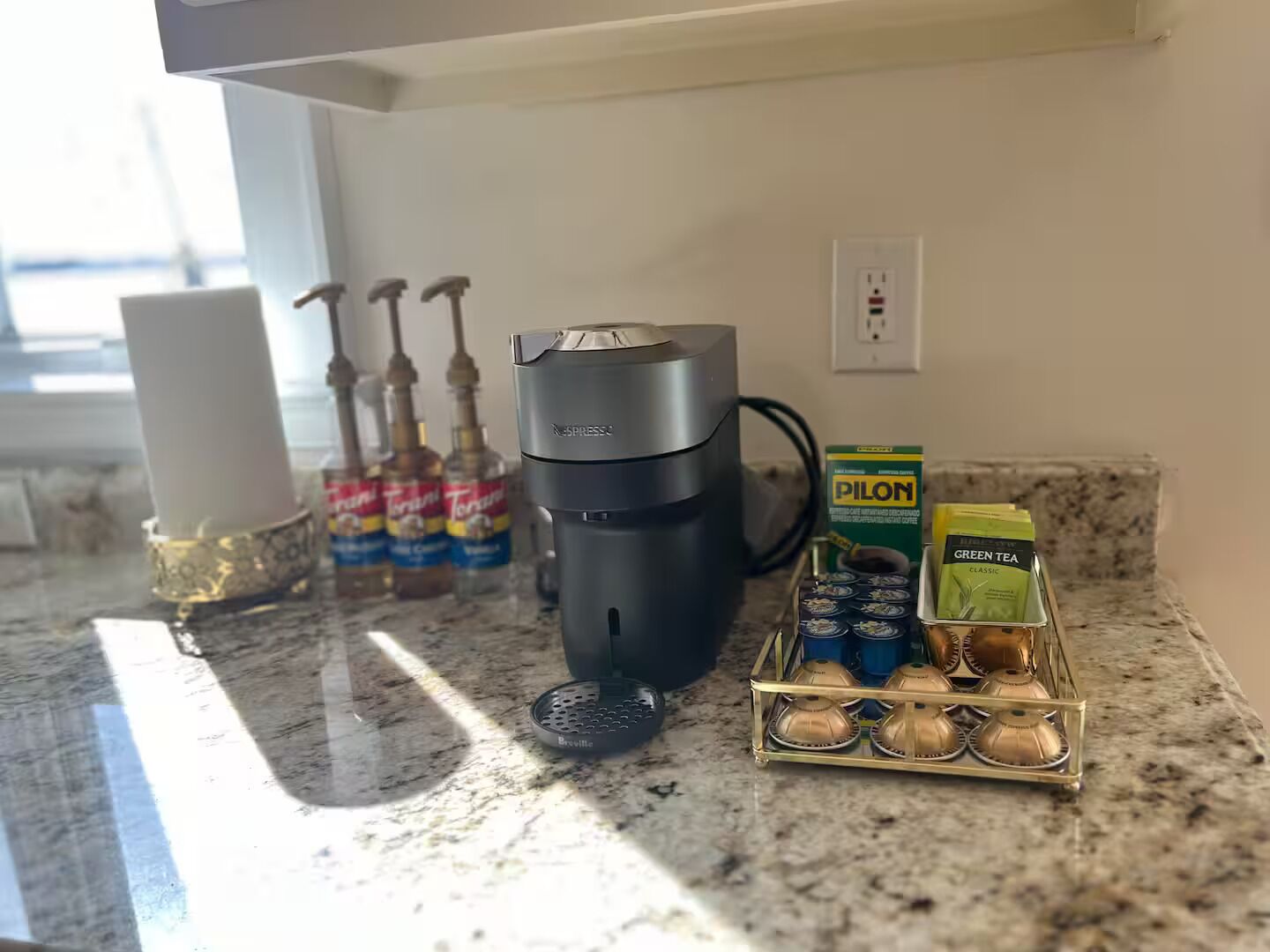 A kitchen counter with a coffee maker, a kettle, and a coffee pod holder.