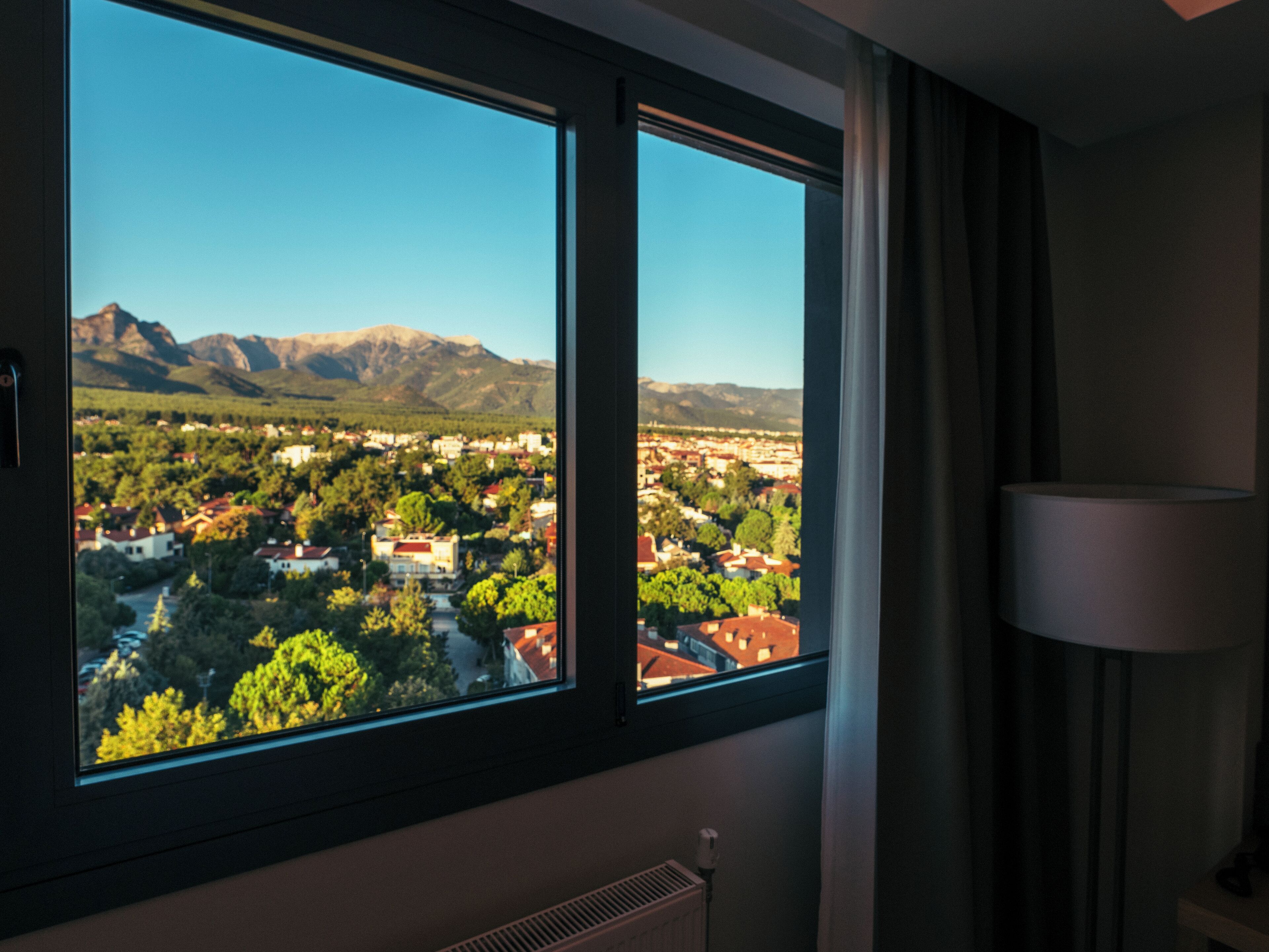 Una habitación con un ventanal grande que da a una ciudad y montañas.