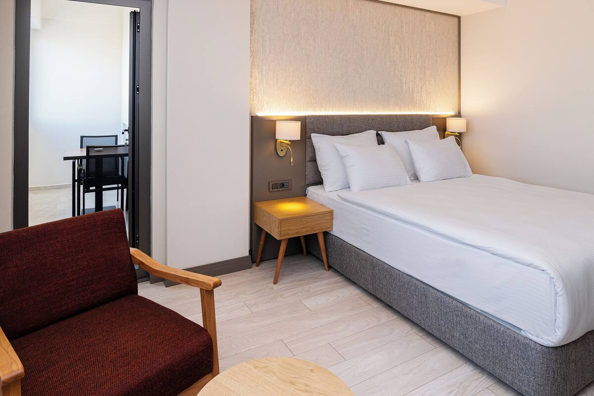 Una habitación de hotel con una cama, una mesita de noche con una lámpara, una silla y una mesa.