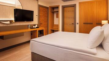 Habitación de hotel con cama, televisor, armario de madera y espejo.