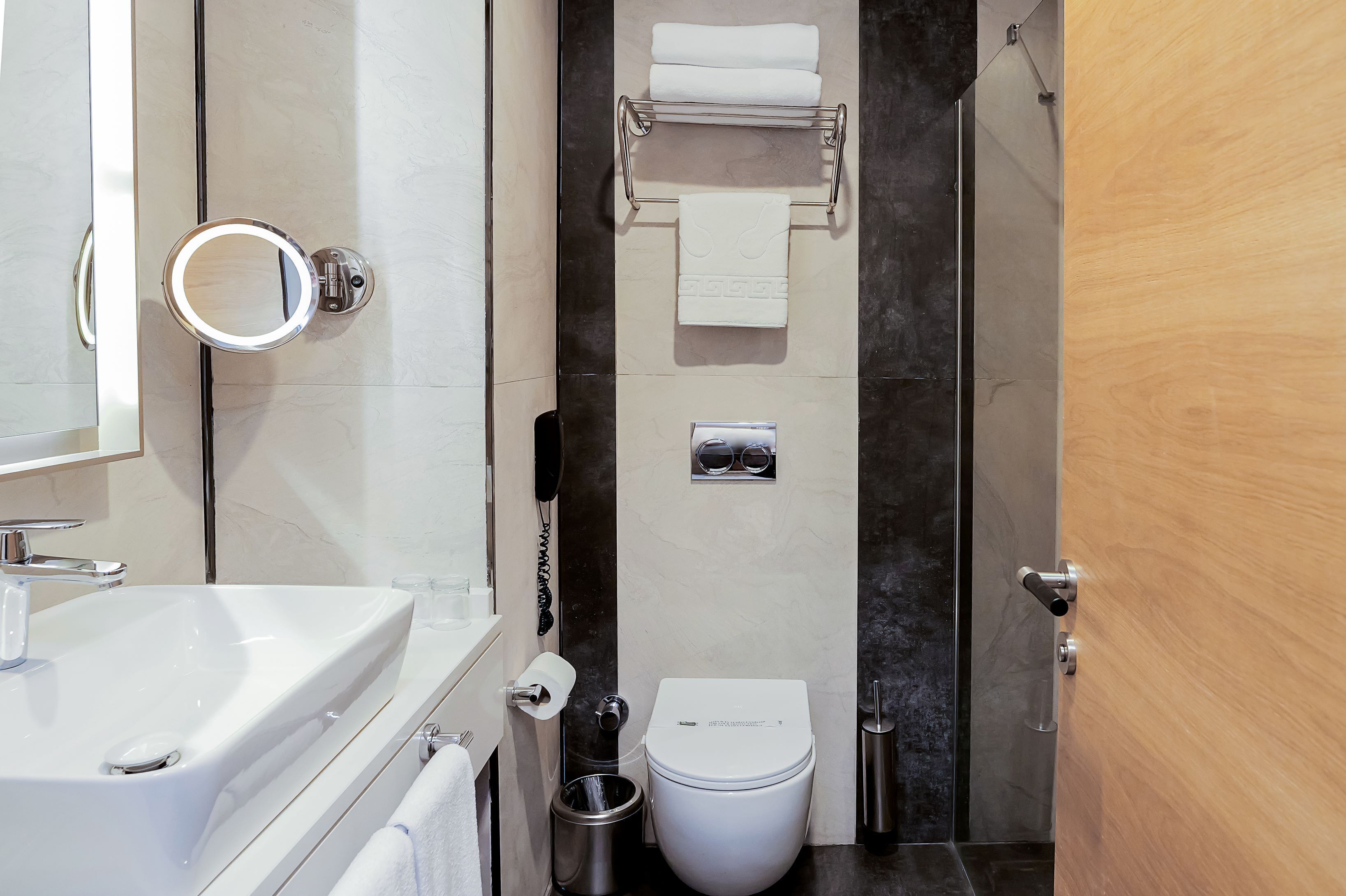 Un baño moderno con lavamanos, inodoro y espejo blancos.