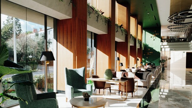 Een ruime lobby met modern meubilair, grote ramen en kamerplanten.