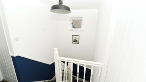 Una escalera con barandillas blancas y una pared azul oscuro.