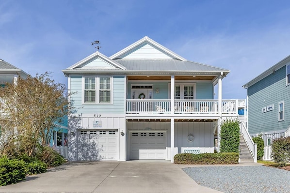 Stunning two-story home with a front porch and balcony, set amidst a beautifully manicured lawn.