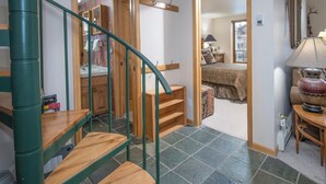 A staircase with wooden steps and green railings leading to a bathroom with a sink and mirror.