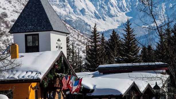 A building with a snow-covered roof and a mountain backdrop.