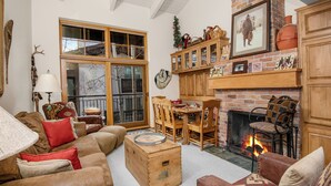 A cozy living room with a fireplace, wooden furniture, and a large window.