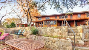 A rustic cabin with a stone wall, outdoor seating, and a staircase leading to the entrance. - Mill Race Lodge I Waterfront, Pool, Wimberley (Wimberley)