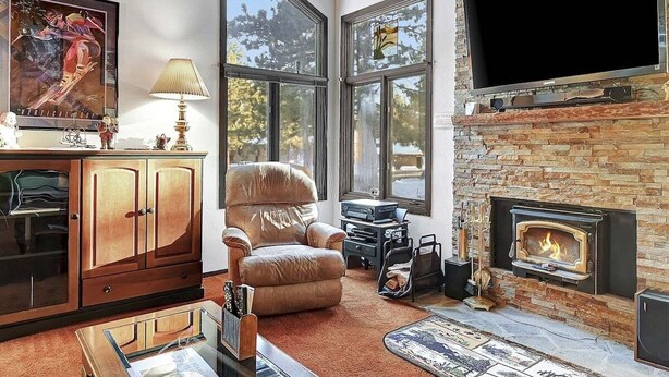 Een gezellige woonkamer met een open haard, een grote televisie en een comfortabele fauteuil.