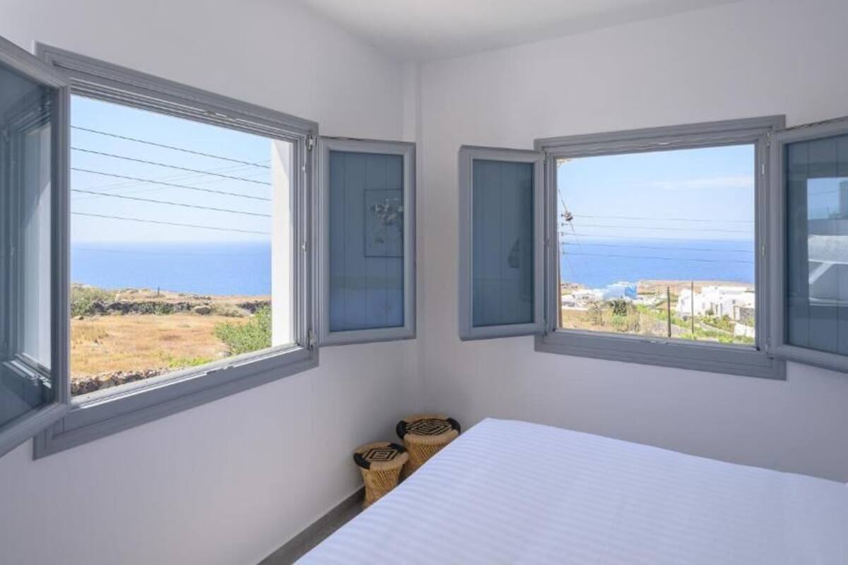 Una camera da letto con due finestre vista mare e un paesaggio lontano.