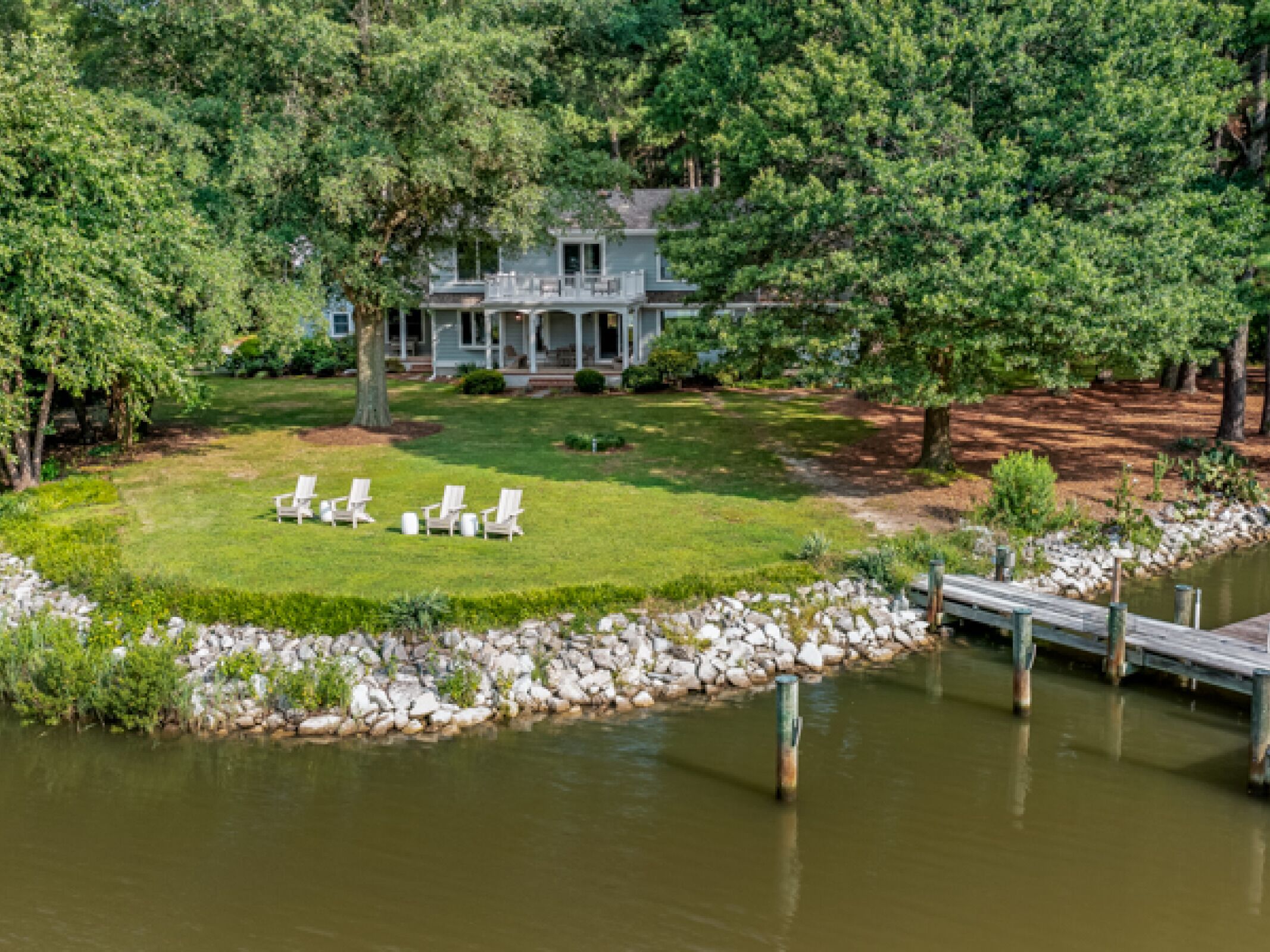 A house with a lawn, a dock, and a pond.