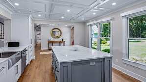 Een moderne keuken met een groot eiland, houten vloeren en uitzicht op de omgeving.