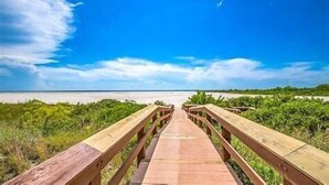 A wooden boardwalk leading to a beach with a clear sky.
