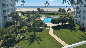A resort with a swimming pool, palm trees, and a view of the beach.